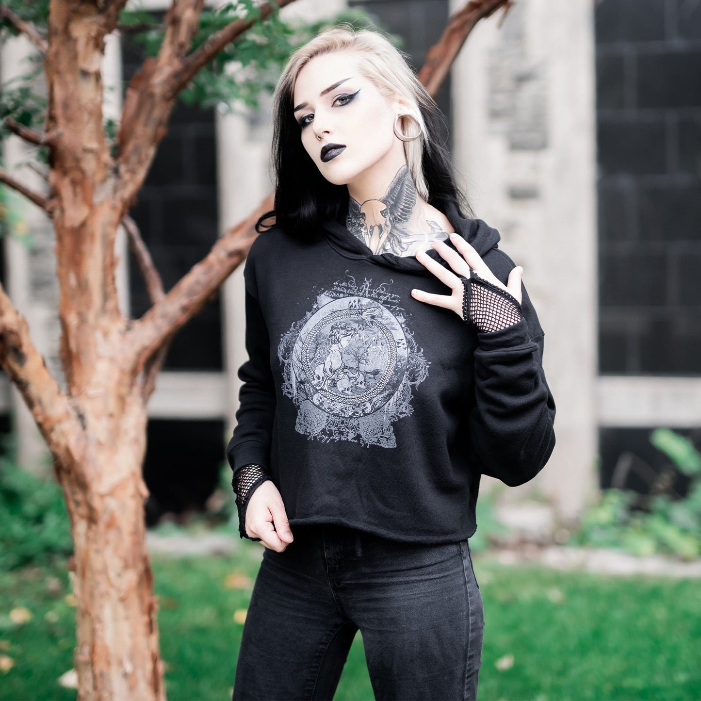 Goth model wearing the Eternal Echoes Graphic Crop Hoodie with Ouroboros and Divine Child design in a Victorian setting.