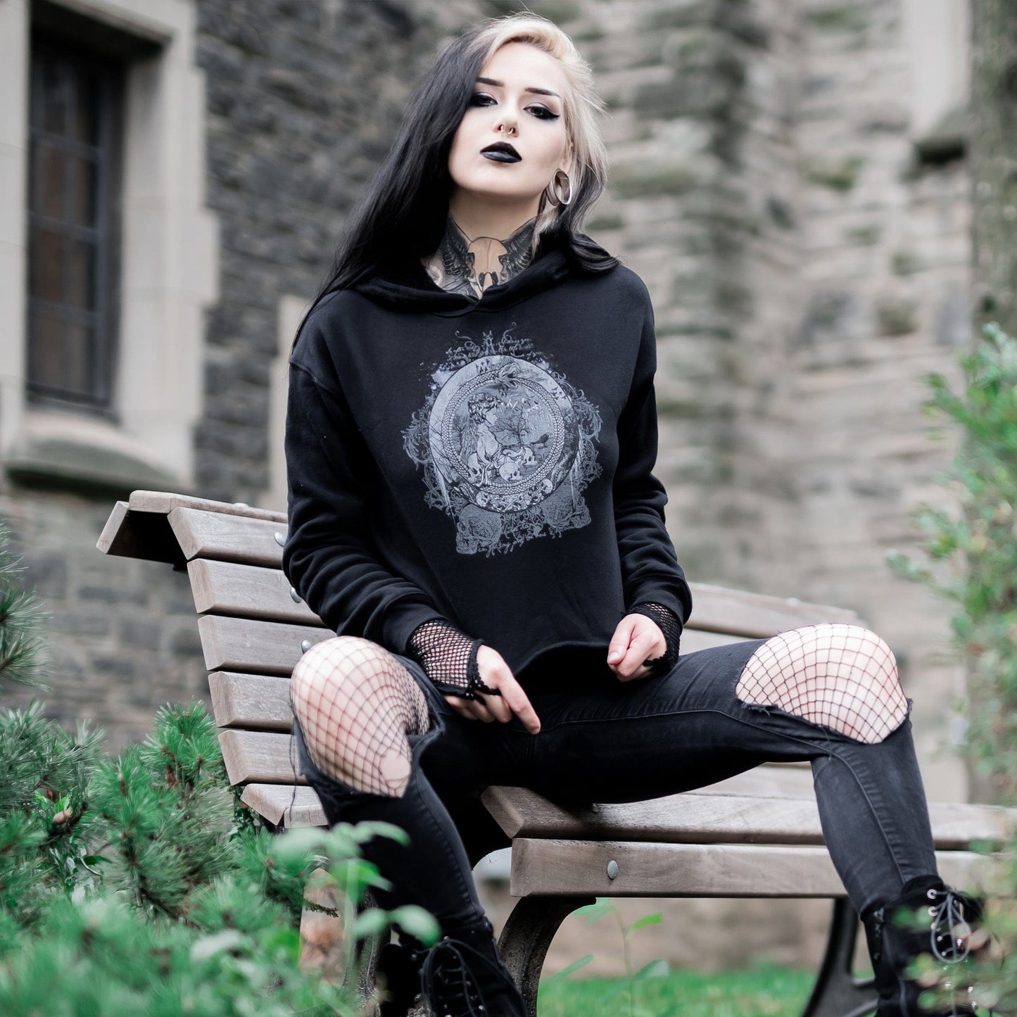 Goth model wearing the Eternal Echoes Graphic Crop Hoodie with Ouroboros and Divine Child design in a Victorian setting.