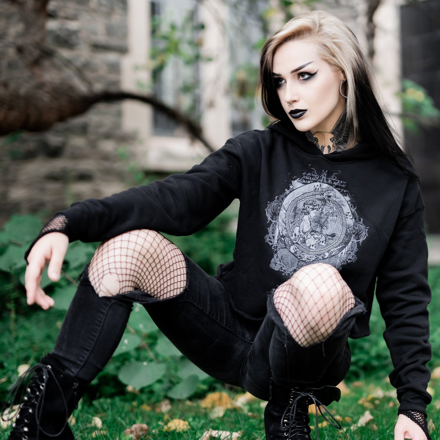 Goth model wearing the Eternal Echoes Graphic Crop Hoodie with Ouroboros and Divine Child design in a Victorian setting.