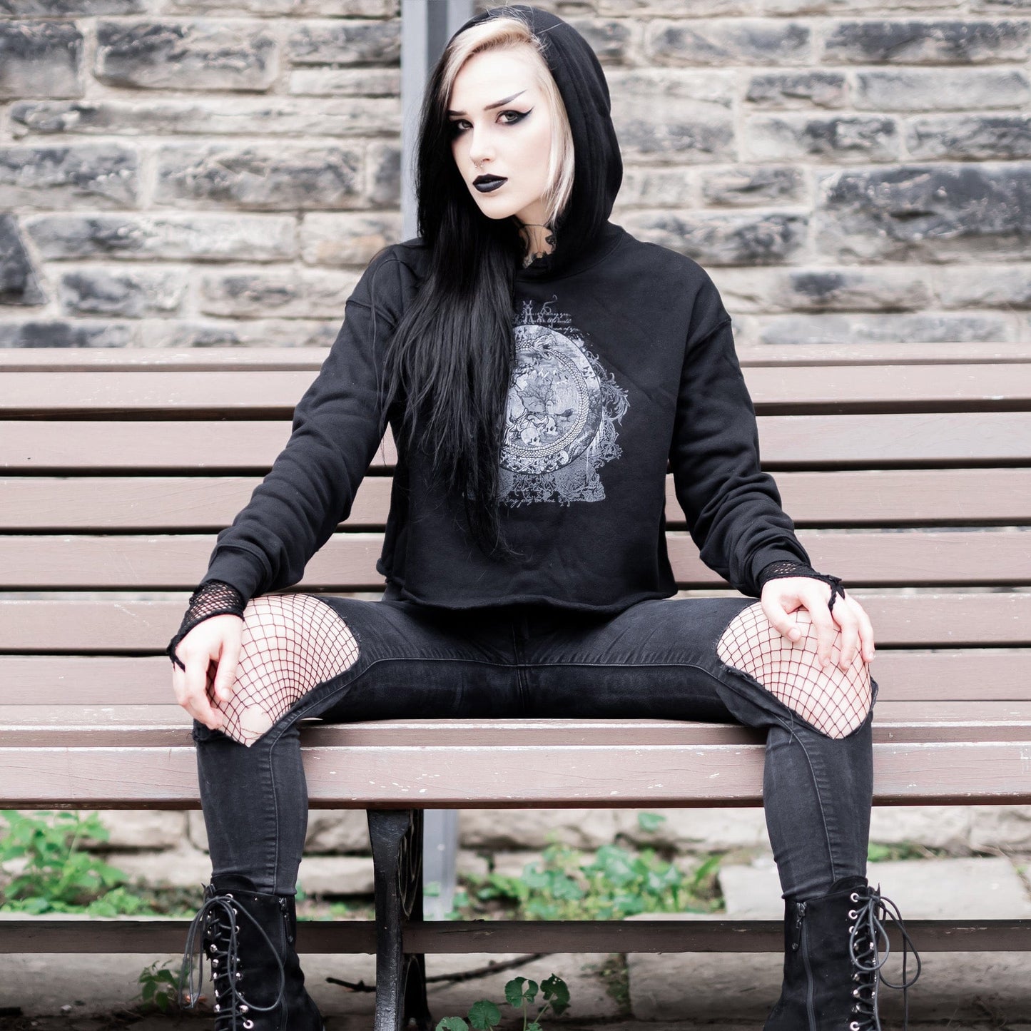Goth model wearing the Eternal Echoes Graphic Crop Hoodie with Ouroboros and Divine Child design in a Victorian setting.
