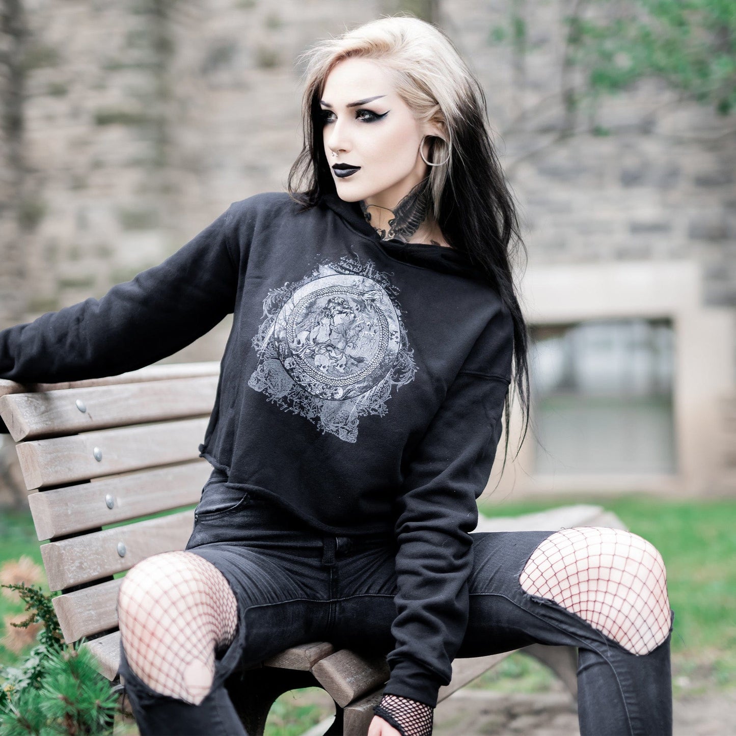Goth model wearing the Eternal Echoes Graphic Crop Hoodie with Ouroboros and Divine Child design in a Victorian setting.