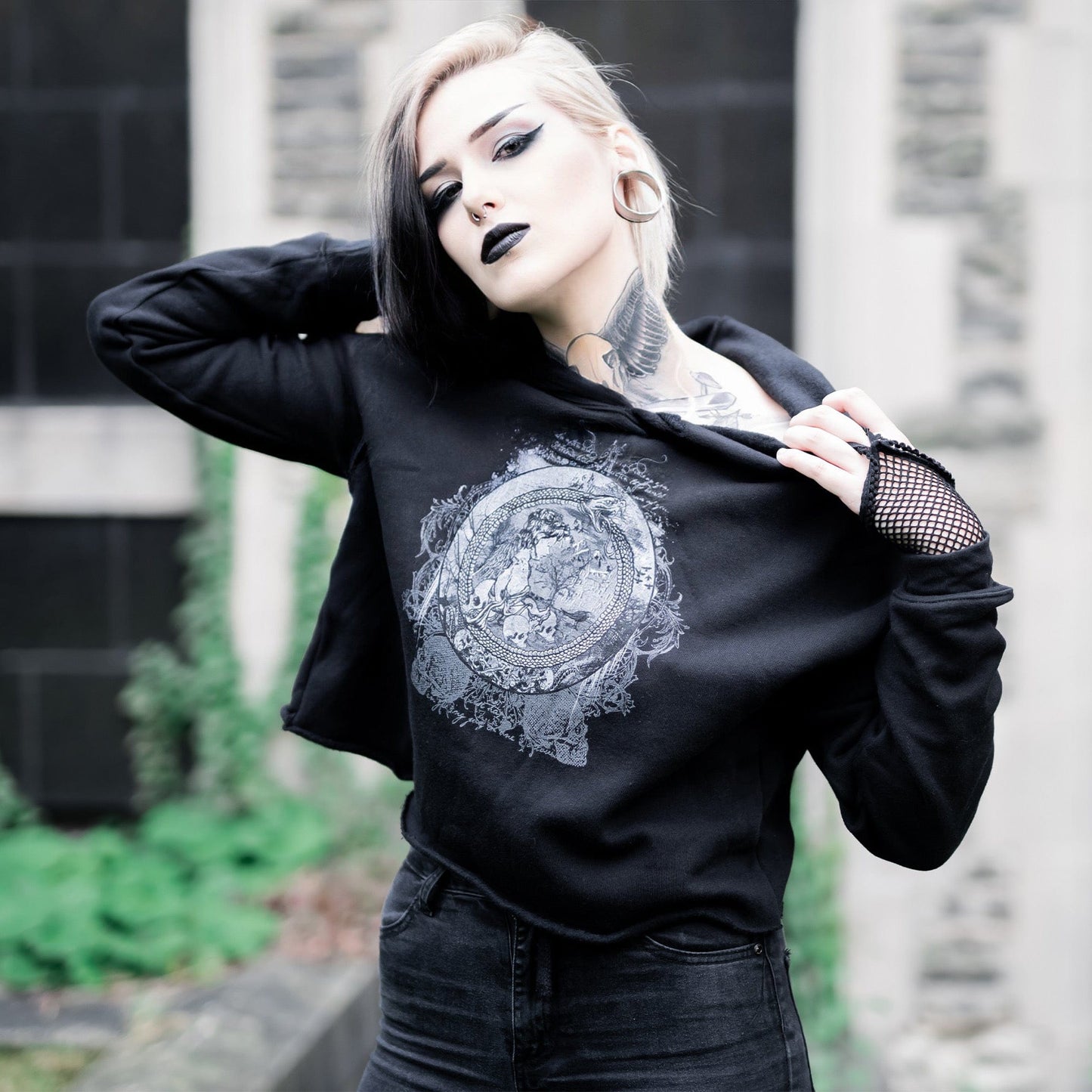 Goth model wearing the Eternal Echoes Graphic Crop Hoodie with Ouroboros and Divine Child design in a Victorian setting.