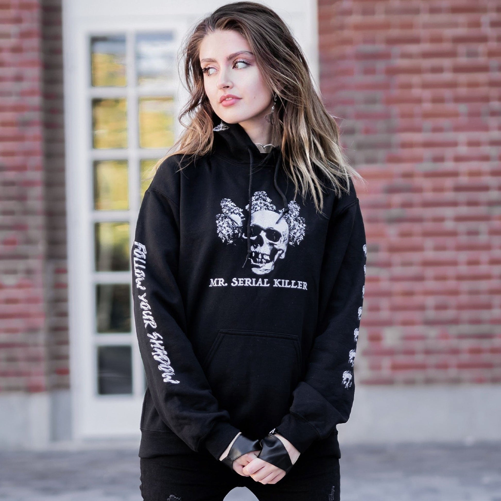 Gothic model wearing the Follow Your Shadow: Mr. Serial Killer Macabre Graphic Black Hoodie in a Victorian setting, embodying dark macabre fashion