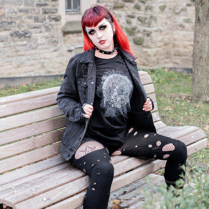 Goth model wearing the Eternal Echoes Graphic T-Shirt with Ouroboros and Divine Child design in a Victorian setting.