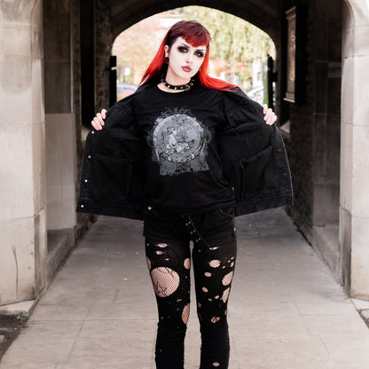 Goth model wearing the Eternal Echoes Graphic T-Shirt with Ouroboros and Divine Child design in a Victorian setting.