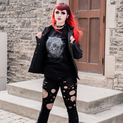 Goth model wearing the Eternal Echoes Graphic T-Shirt with Ouroboros and Divine Child design in a Victorian setting.