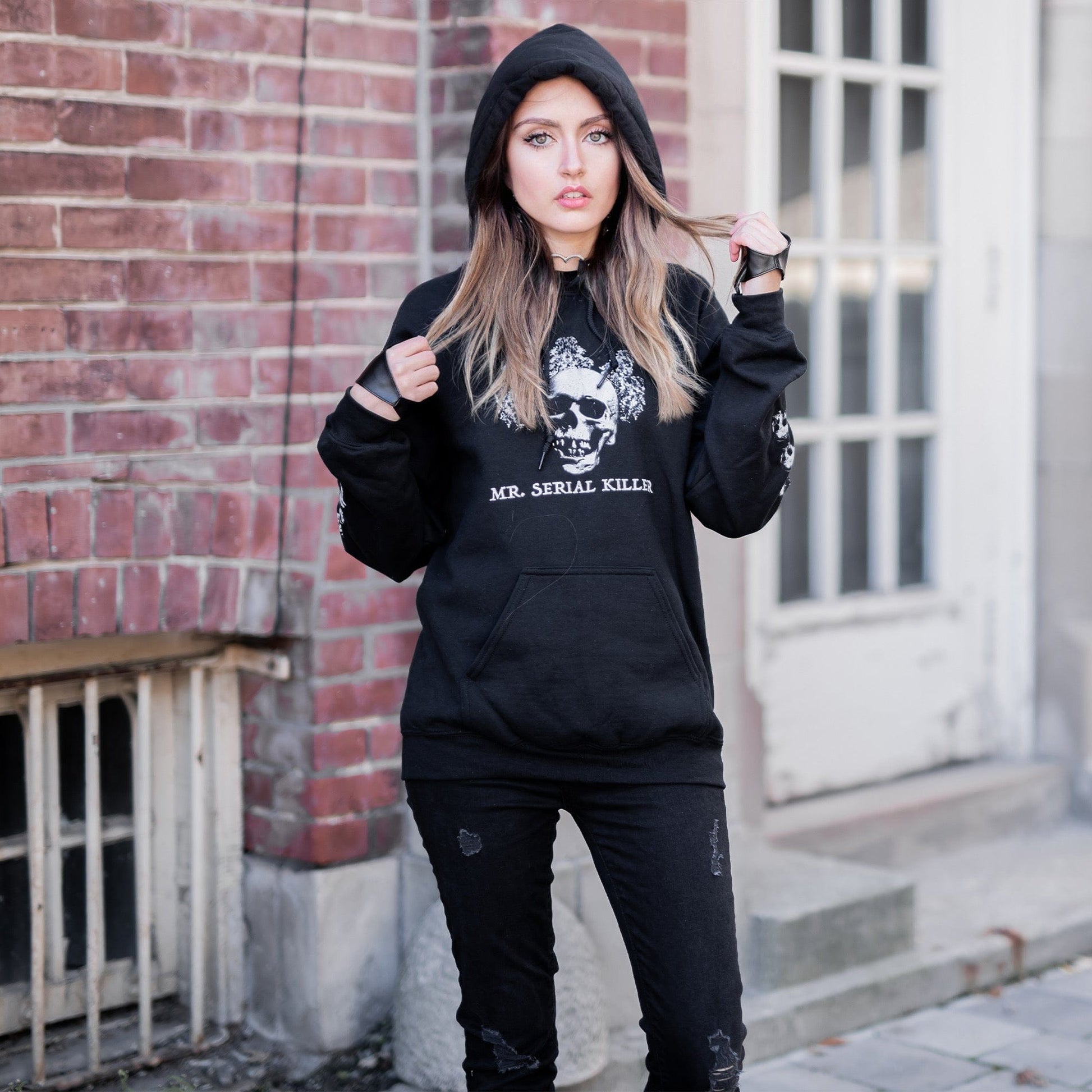 Gothic model wearing the Follow Your Shadow: Mr. Serial Killer Macabre Graphic Black Hoodie in a Victorian setting, embodying dark macabre fashion