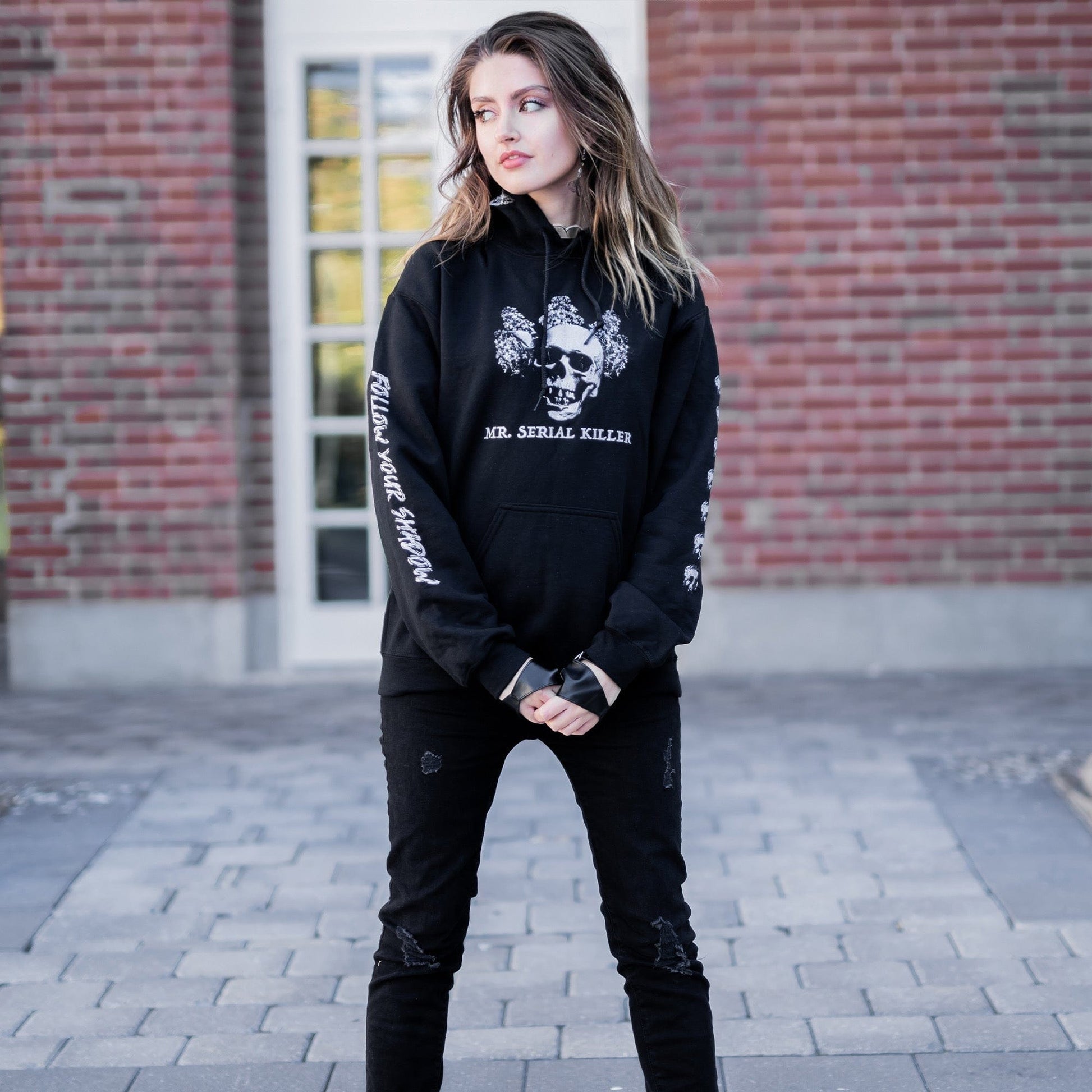 Gothic model wearing the Follow Your Shadow: Mr. Serial Killer Macabre Graphic Black Hoodie in a Victorian setting, embodying dark macabre fashion