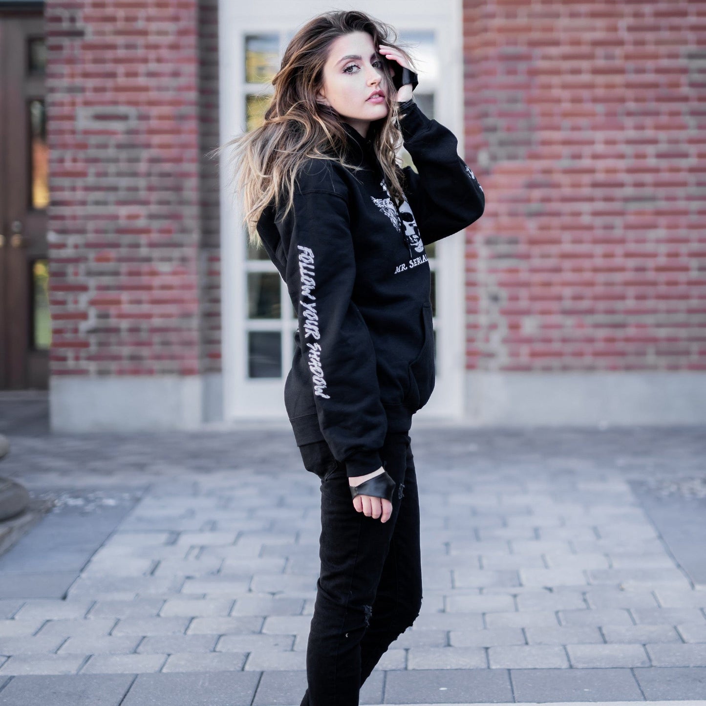 Gothic model wearing the Follow Your Shadow: Mr. Serial Killer Macabre Graphic Black Hoodie in a Victorian setting, embodying dark macabre fashion