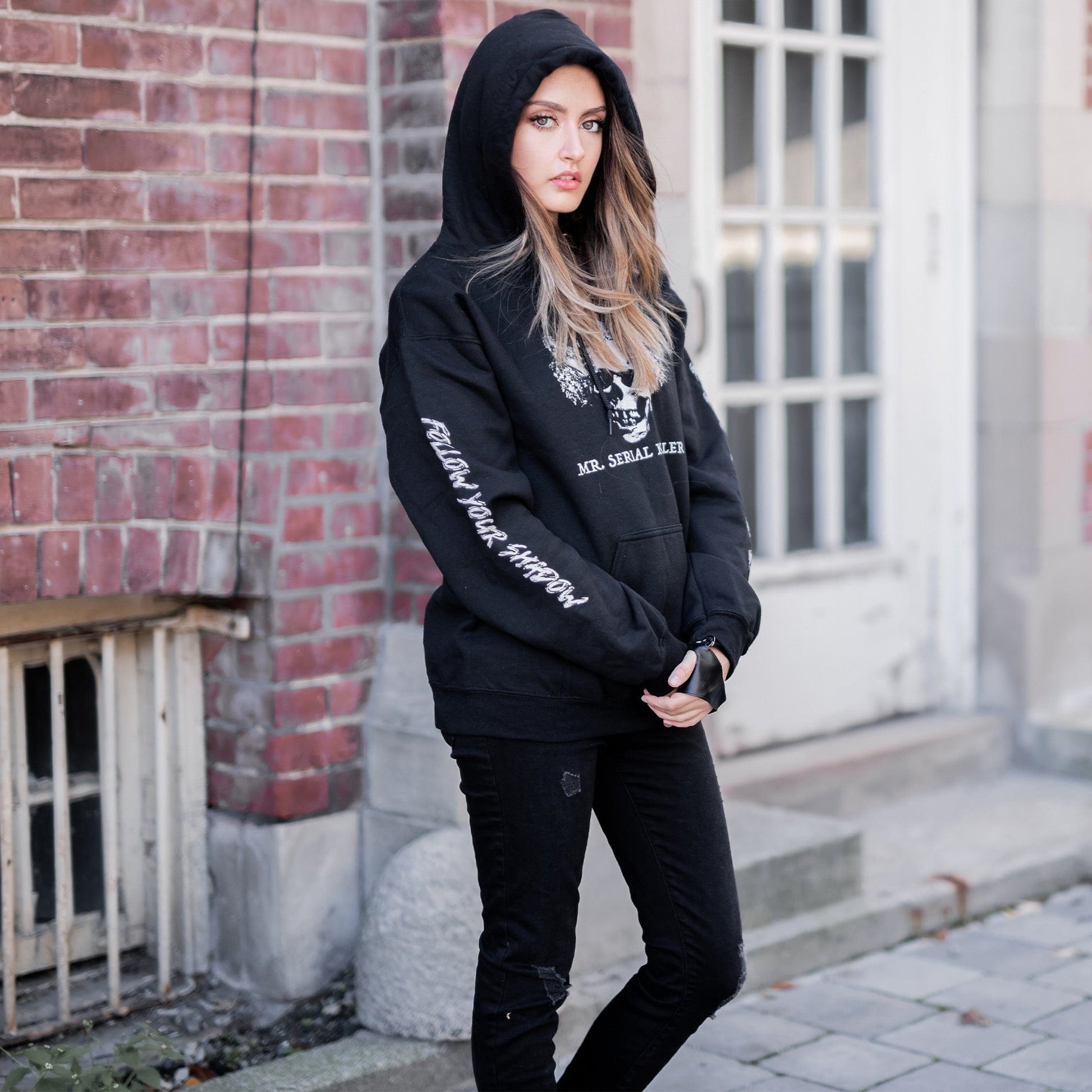 Gothic model wearing the Follow Your Shadow: Mr. Serial Killer Macabre Graphic Black Hoodie in a Victorian setting, embodying dark macabre fashion