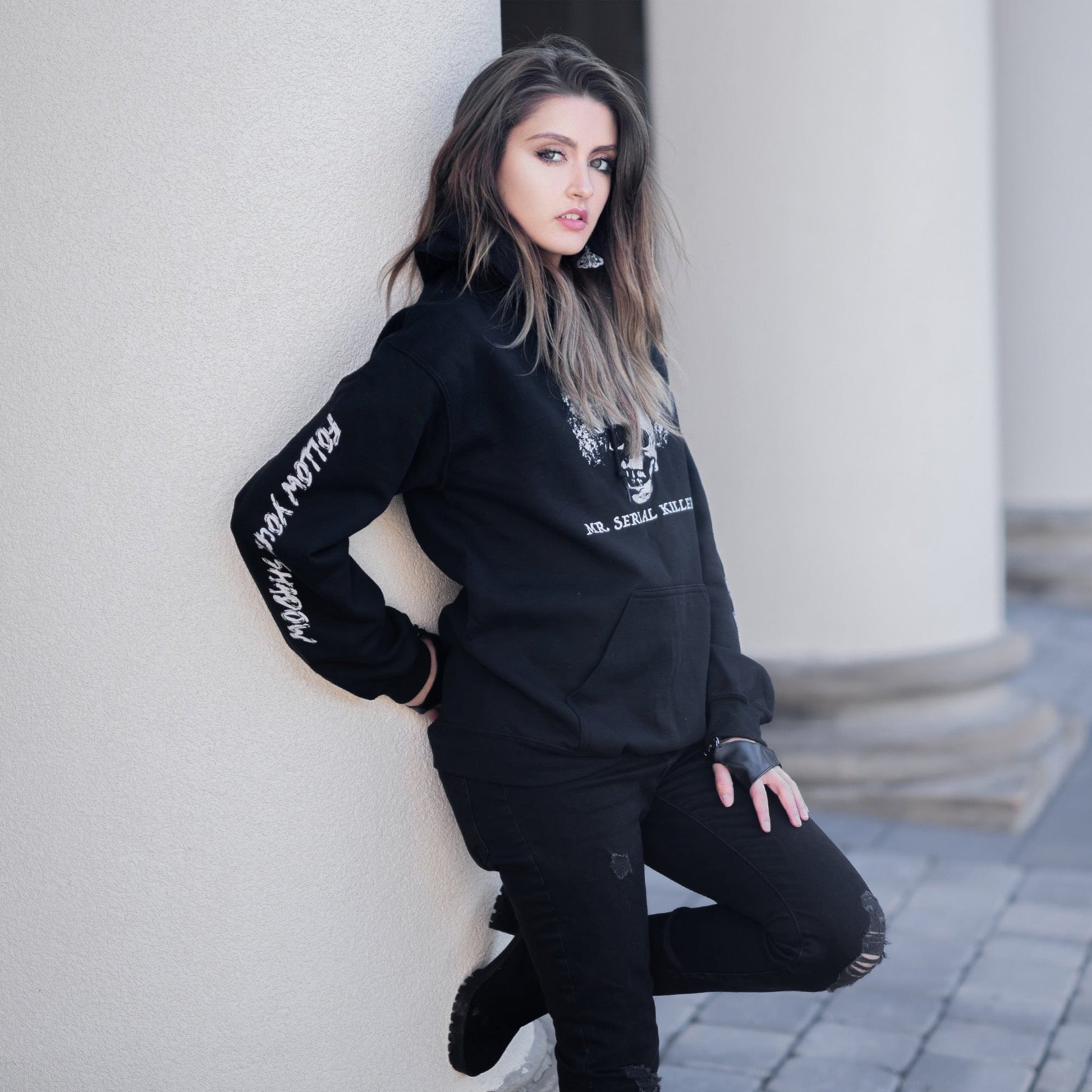 Gothic model wearing the Follow Your Shadow: Mr. Serial Killer Macabre Graphic Black Hoodie in a Victorian setting, embodying dark macabre fashion