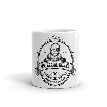 Mockup of the 'Follow Your Shadow' coffee mug featuring Mr. Serial Killer with a custom illustration and show logo, available in glossy white with black print, in 11oz and 15oz sizes.